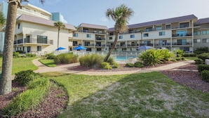 Um hotel com várias varandas, piscina e jardins bem cuidados.