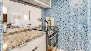 Uma cozinha com bancada de granito, eletrodomésticos de aço inoxidável e azulejos de mosaico azuis.