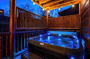 A hot tub with a wooden deck and railings, surrounded by a wooden fence. - Bethlehem Lodge (Sevierville)