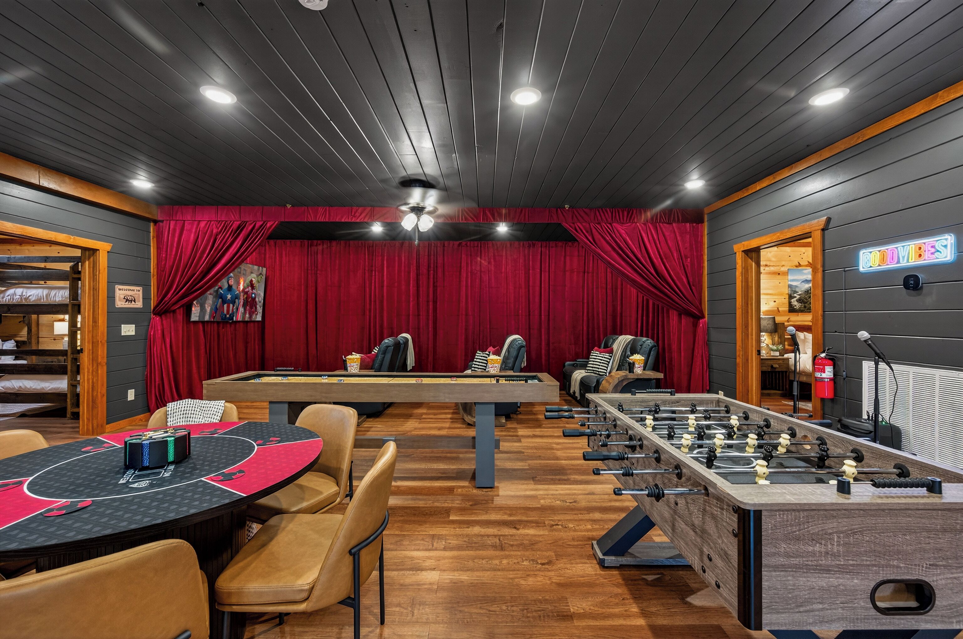 A room with a foosball table, a pool table, and a long table with chairs.