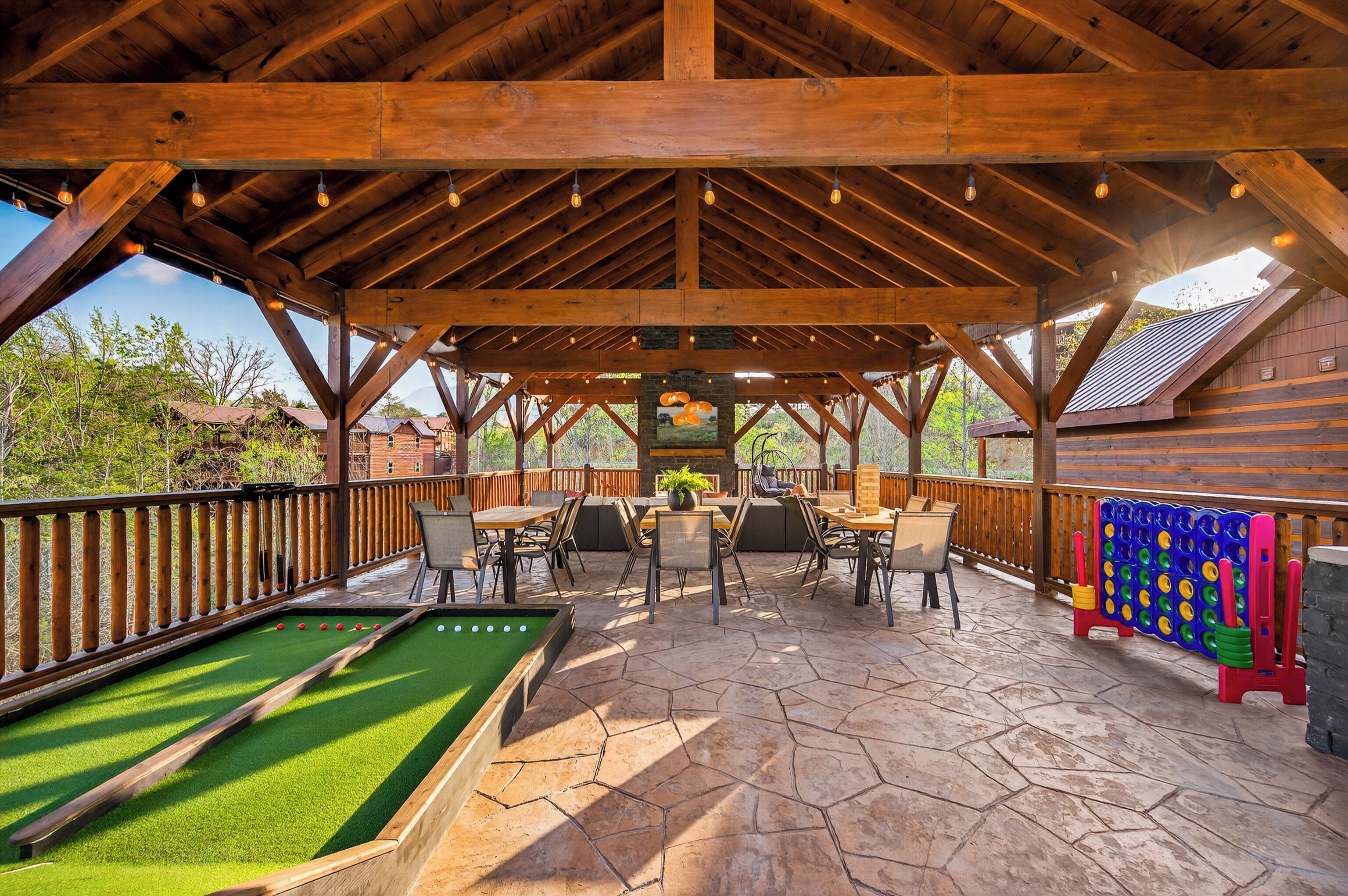 Un espacio al aire libre techado con mesa de billar, asientos y juego de shuffleboard.