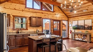A spacious kitchen with wooden cabinets, a granite countertop, and a large island with bar stools. - Bethlehem Lodge (Sevierville)
