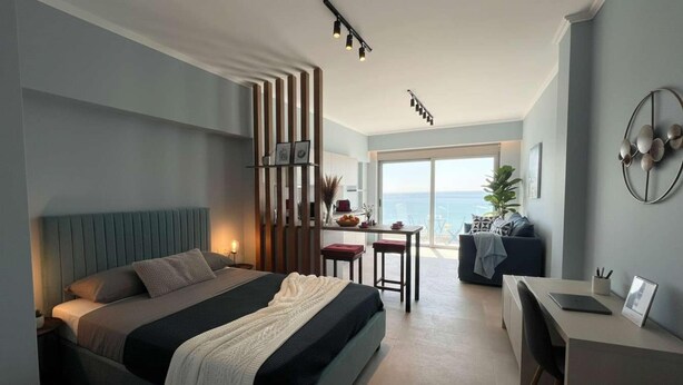 Una camera d'albergo moderna con un letto, una scrivania, una sedia e vista sul mare.