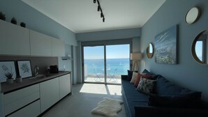 Un interno moderno con una cucina, un divano, un'ampia finestra e vista mare.