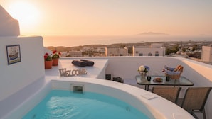 A rooftop terrace with a swimming pool, a welcome sign, a table with a basket of bread, and a view of the city and mountains in the distance. - Fira Home With Rooftop Hot Tub (Santorini)