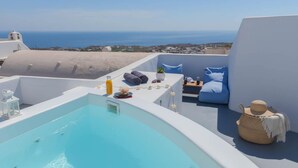 A rooftop pool area with a view of the sea, a lounge with a sofa and a small table, and a wicker basket. - Fira Home With Rooftop Hot Tub (Santorini)