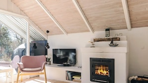 A living room with a fireplace, a television, and a chair. - 4 Person Holiday Home in Gilleleje (Gilleleje)