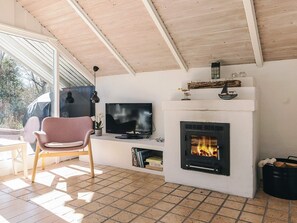 Ein Wohnzimmer mit Kamin, Fernseher und einem Sessel.