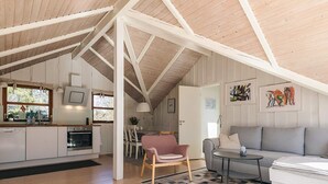 A spacious loft with a high ceiling, a kitchen with modern appliances, a dining area, and a living room with a sofa and a small table. - 4 Person Holiday Home in Gilleleje (Gilleleje)