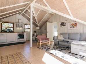 Ein geräumiges Loft mit hohen Decken, einer Küche mit modernen Geräten, einem Essbereich und einem Wohnzimmer mit einer Couch und einem kleinen Tisch.