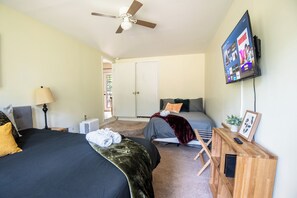 A bedroom with two beds, a ceiling fan, a TV mounted on the wall, and a bedside table with a remote control. - The Garden Park Escape: Pool/Patio/Groups/King Bed (Birmingham)