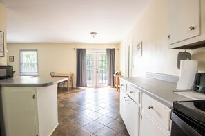 A kitchen with a dining table, chairs, a microwave, and a stove. - The Garden Park Escape: Pool/Patio/Groups/King Bed (Birmingham)