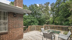 A wooden deck with a brick building, a pool, and two chairs. - The Poolside Haven | Family/Backyard/Game Room Fun (Birmingham)