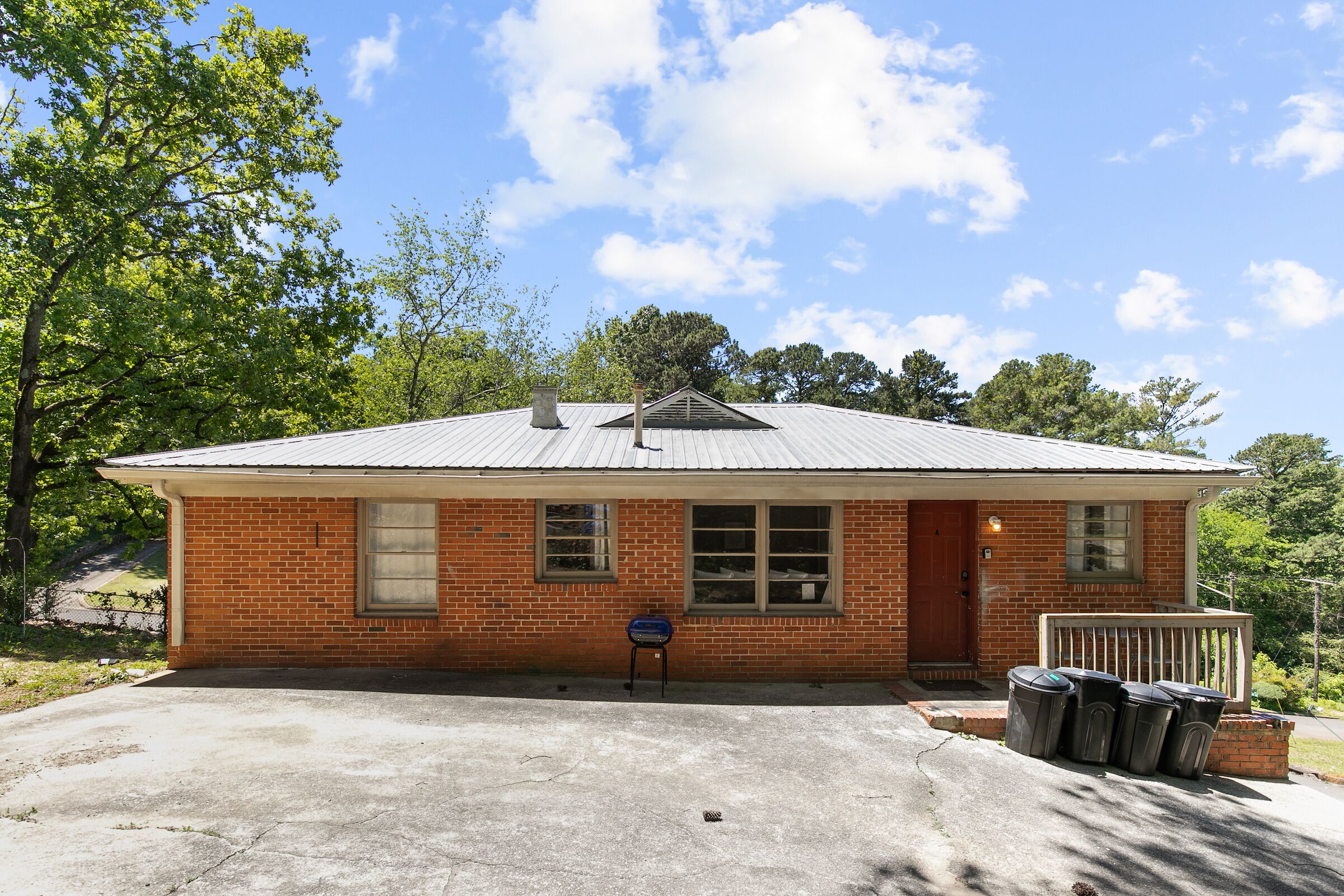 A small brick building with a metal roof, a front door, and a mailbox.