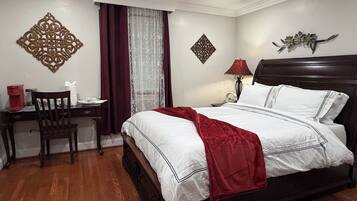 Quarto bem arrumado com cama, mesa de cabeceira, cadeira e detalhes decorativos na parede.