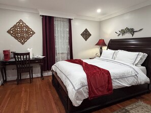 A neatly arranged bedroom with a bed, bedside table, chair, and decorative wall pieces.