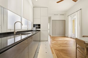 A modern kitchen with a large island, a built-in oven, and a wooden herringbone floor. - 1905 Corner Flat · Temporary Stay · Las Letras (Madrid)