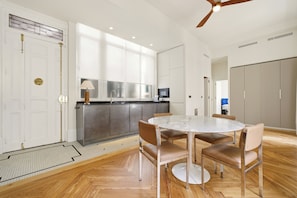 A modern kitchen with a dining area, wooden flooring, and a ceiling fan. - 1905 Corner Flat · Temporary Stay · Las Letras (Madrid)