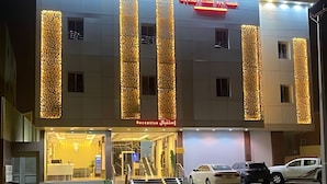 Un hotel con recepción, una escalera y coches aparcados.