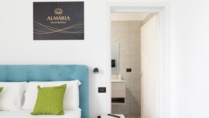 Ein Hotelzimmer mit einem Bett, einem Nachttisch, einer Wandleuchte, einem Spiegel und einem durchgehenden Türspalt sichtbaren Badezimmer.