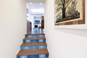 Eine Treppe mit blauen und weißen Mustern, die zu einem Küchenbereich mit modernen Geräten und einem Esstisch führt.