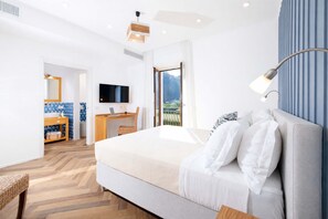 A modern hotel room with a large bed, a desk, a television, and a view of the outdoors. - Appartamento Seapearl Sorrento (Sorrento)