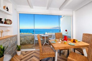 A dining area with wicker chairs, a wooden table, and a view of the sea. - Appartamento Seapearl Sorrento (Sorrento)