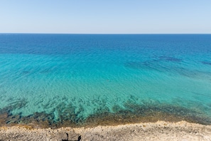 A coastal landscape with clear turquoise waters, a rocky shoreline, and a clear sky. - Apartment 'Residence La Perla - Rubino' with Balcony and Air Conditioning (Marina di Mancaversa)