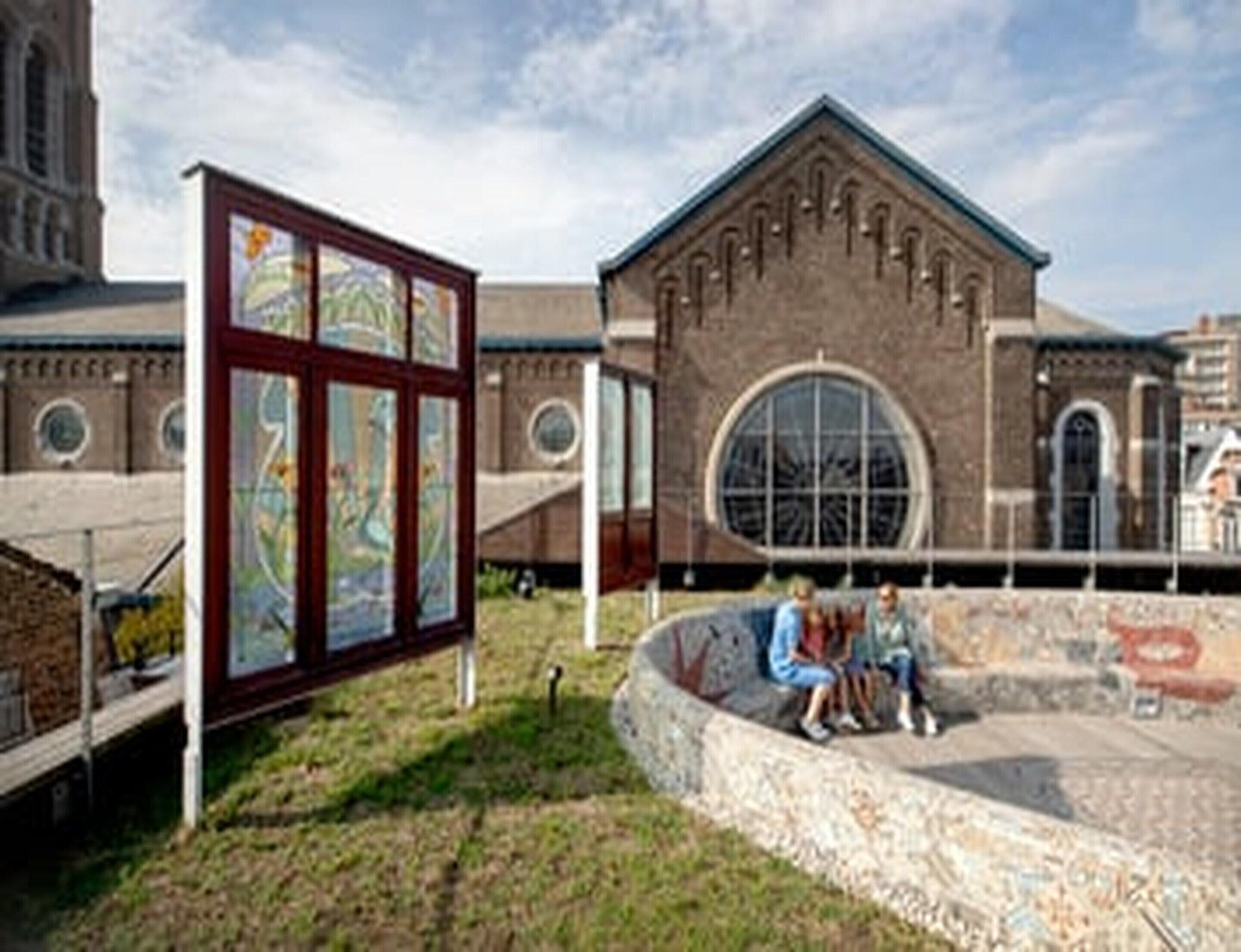 Un edifici amb una gran finestra apuntada i un mural a la façana.