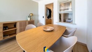 Una habitación moderna con una mesa de comedor de madera, sillas blancas, un armario empotrado y un ventanal con vistas.