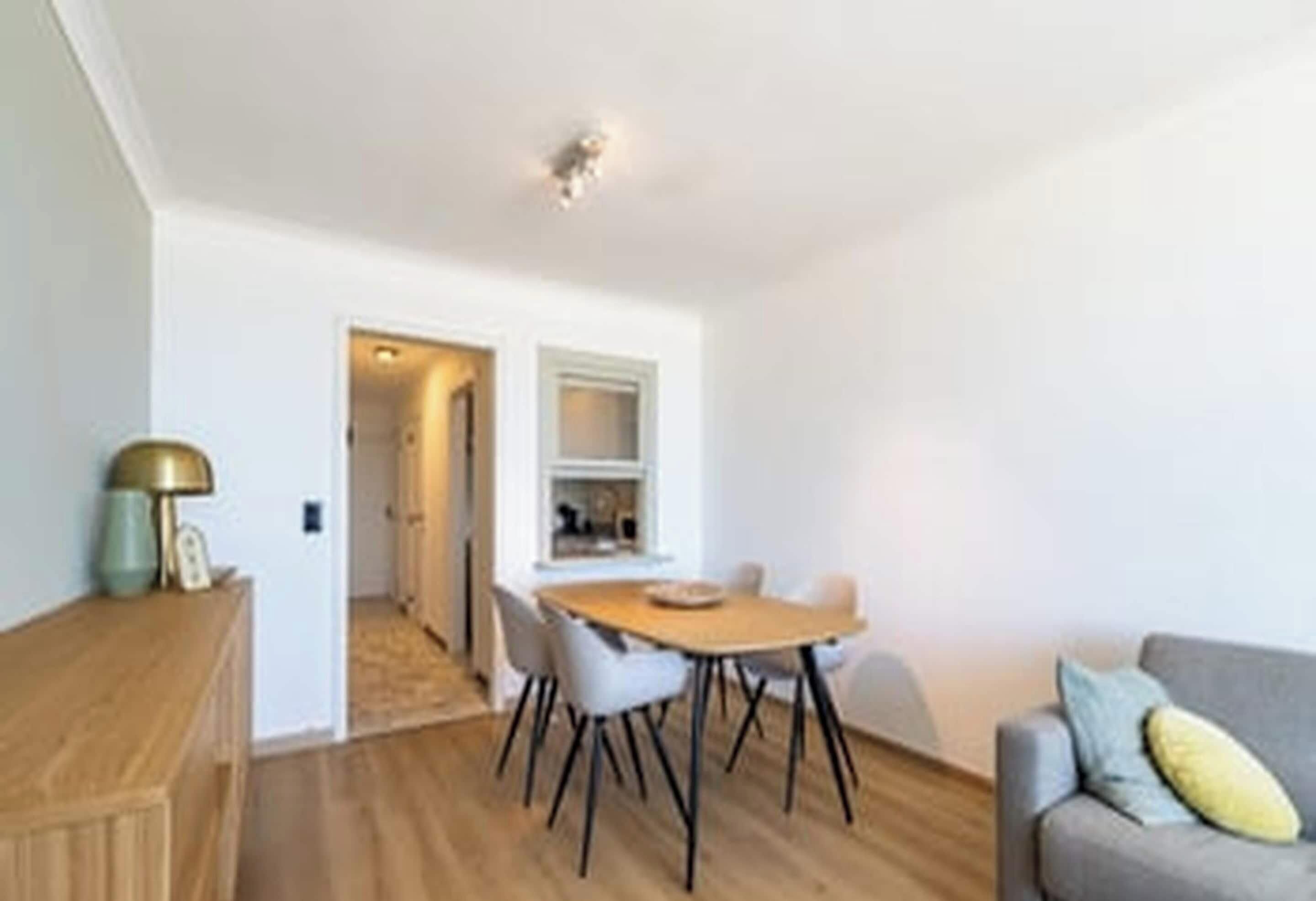 A modern living room with a dining table and chairs, a sofa, and a wooden cabinet.