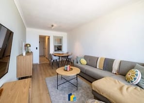 Un salon moderne avec un canapé, une table basse et un téléviseur.