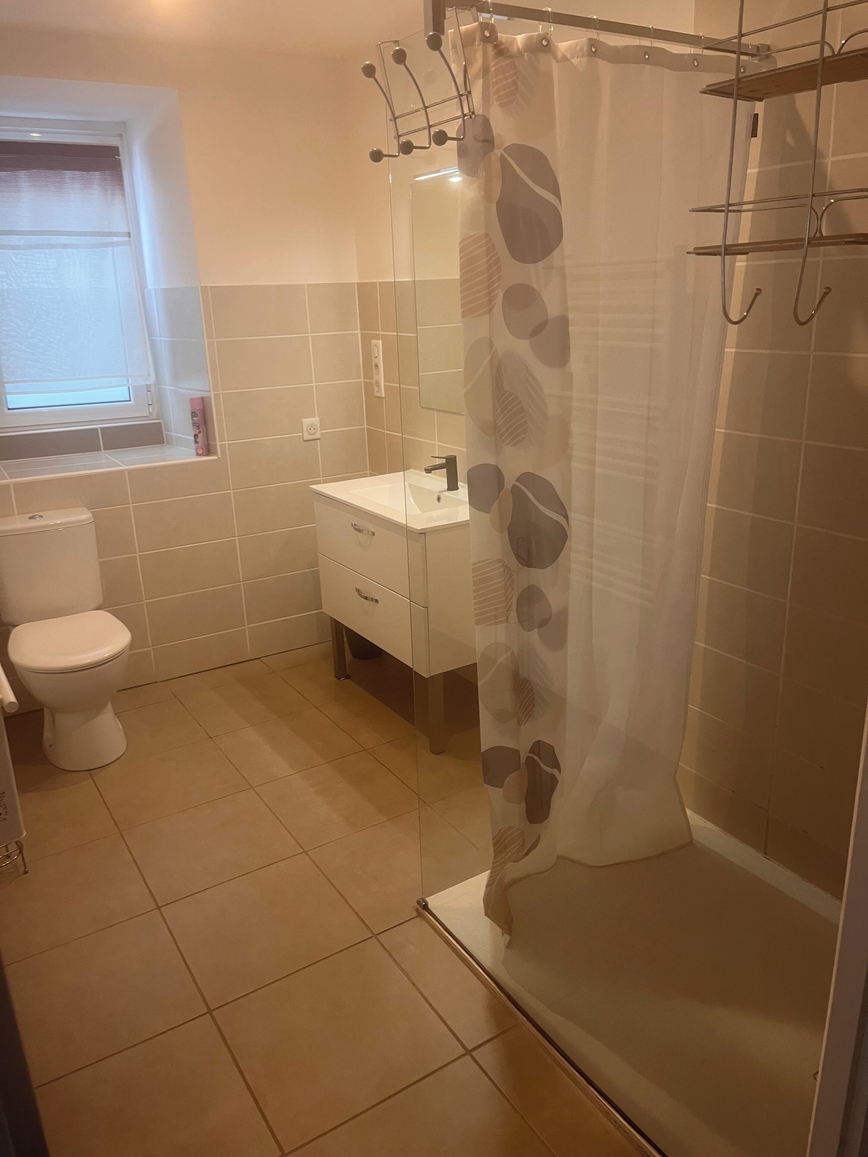 Un baño con inodoro, lavamanos y cortina de ducha.