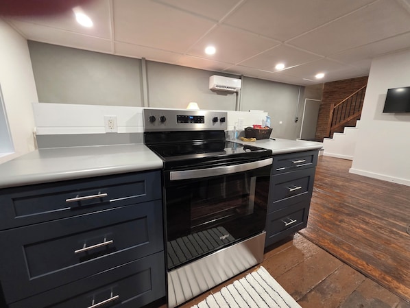A kitchen with a built-in oven, a microwave, and a range hood. There is a wooden floor and a white countertop.