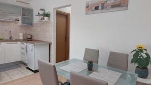 A modern kitchen with white cabinets, a small refrigerator, and a countertop with a sink. - Boutique Studio Pula (Pula)