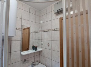 A bathroom with a white sink, mirror, and a shower area. - Boutique Studio Pula (Pula)