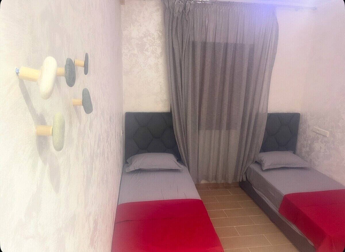 A room with two beds, a curtain, and a wall-mounted massage device.