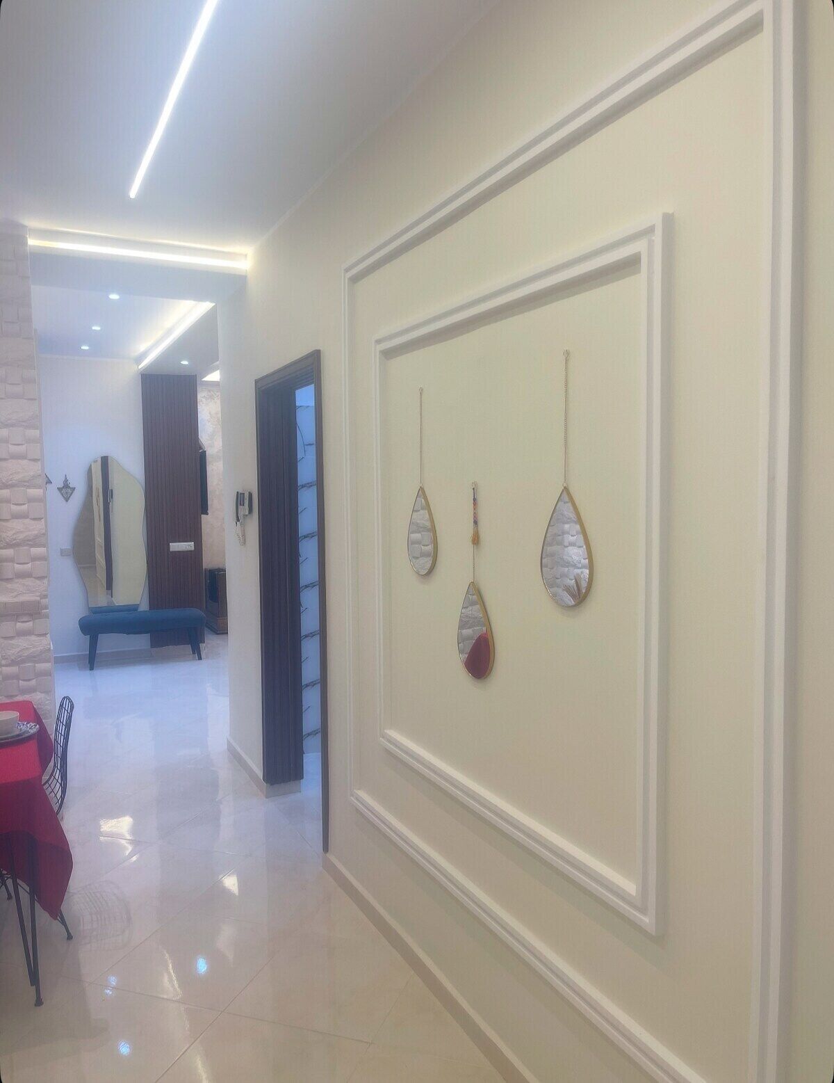 A hallway with a bench, a table with chairs, and wall-mounted decorative items.