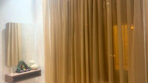 A bathroom with a beige curtain, a mirror, a shelf with toiletries, and a white bench. - Modern Wi-Fi, Agadir, 10 min Beach, Netflix, IPTV, First floor. 93m2. Balcony. (Agadir)