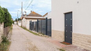 A narrow street with a gravel path, a black metal fence, and a building with a white facade and a black door. - Spacious Studio 2P - Benerville (Benerville-sur-Mer)