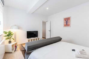 A hotel room with a bed, a TV, a lamp, a plant, and a poster on the wall. - Spacious Studio 2P - Benerville (Benerville-sur-Mer)