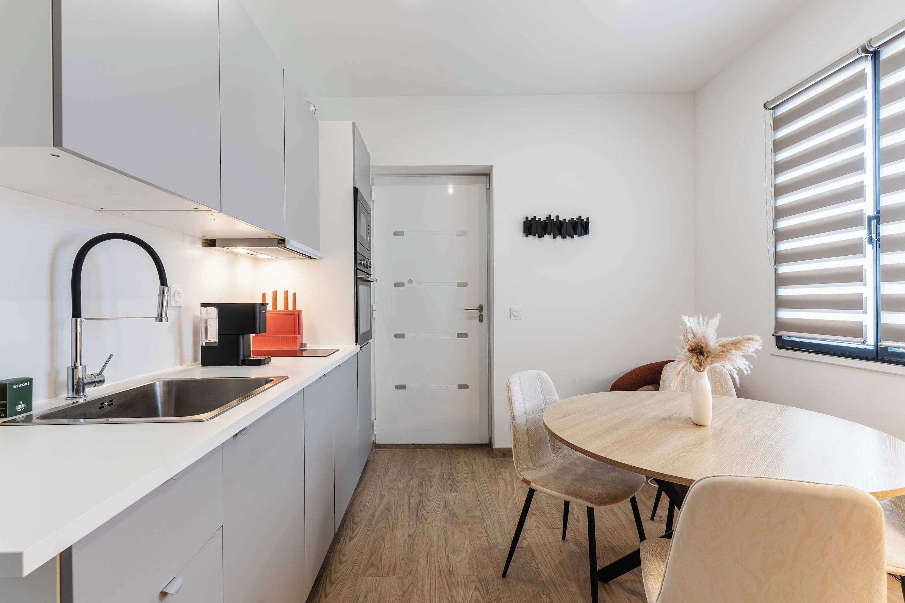A modern kitchen with a sink, stove, and dining area with chairs and a table.