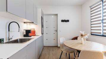 A modern kitchen with a sink, stove, and dining area with chairs and a table.