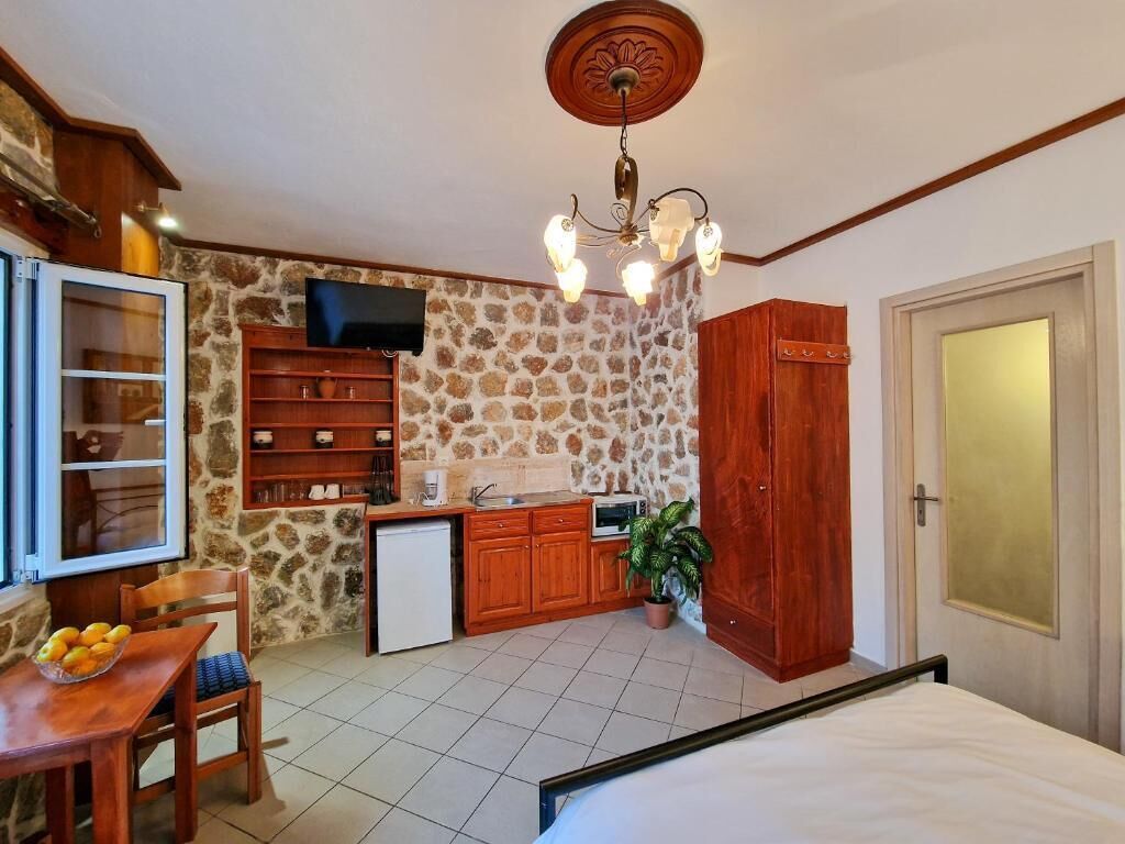 Una habitación compacta con cama, un pequeño kitchenette, televisión y una pared de piedra.