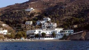 A coastal building complex with multiple structures, some with balconies, situated on a hillside overlooking the sea.