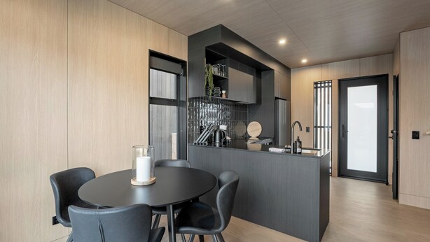 Una cocina moderna con una isla central, sillas negras y una mesa de comedor redonda.