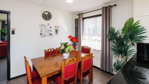Ein Essbereich mit Holztisch, rot gepolsterten Stühlen, einer Wanduhr und einem Blumentopf.