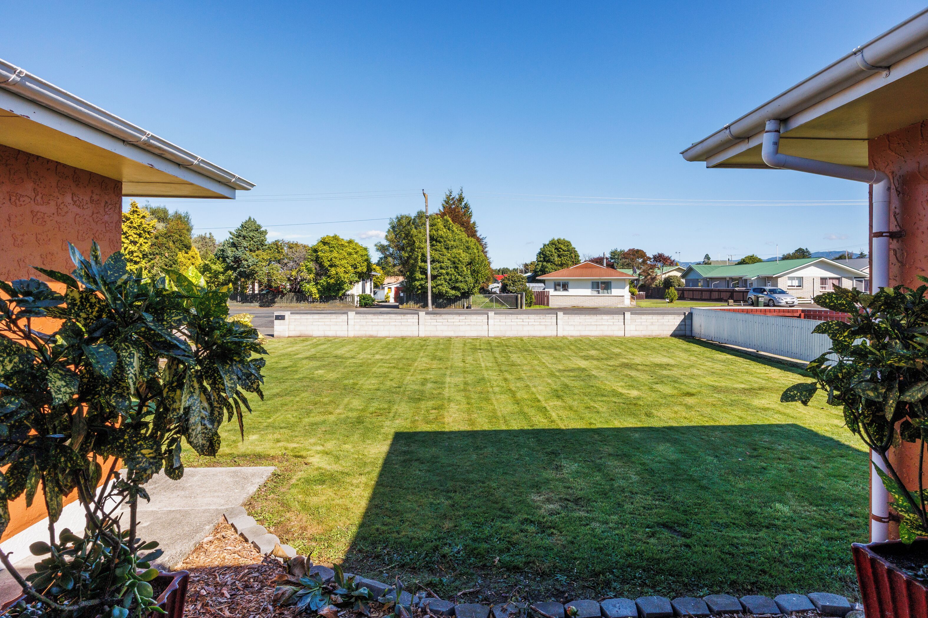 A well-maintained lawn, a brick wall, and a clear sky.