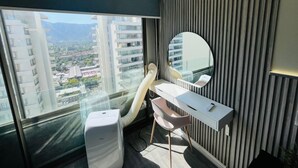 A modern hotel room with a large window, a desk, a chair, and a round mirror. - Dummy Malaga (Santiago)