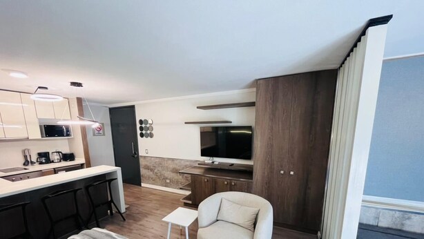A modern hotel room with a kitchenette, a sofa, a small table, and a TV. - Dummy Malaga (Santiago)